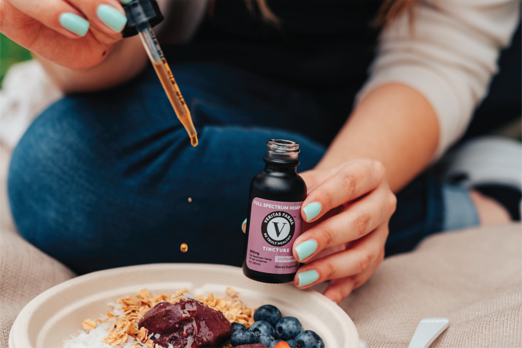 Person Adding Veritas Farms Tincture Drops to their Oatmeal | Veritas Farms