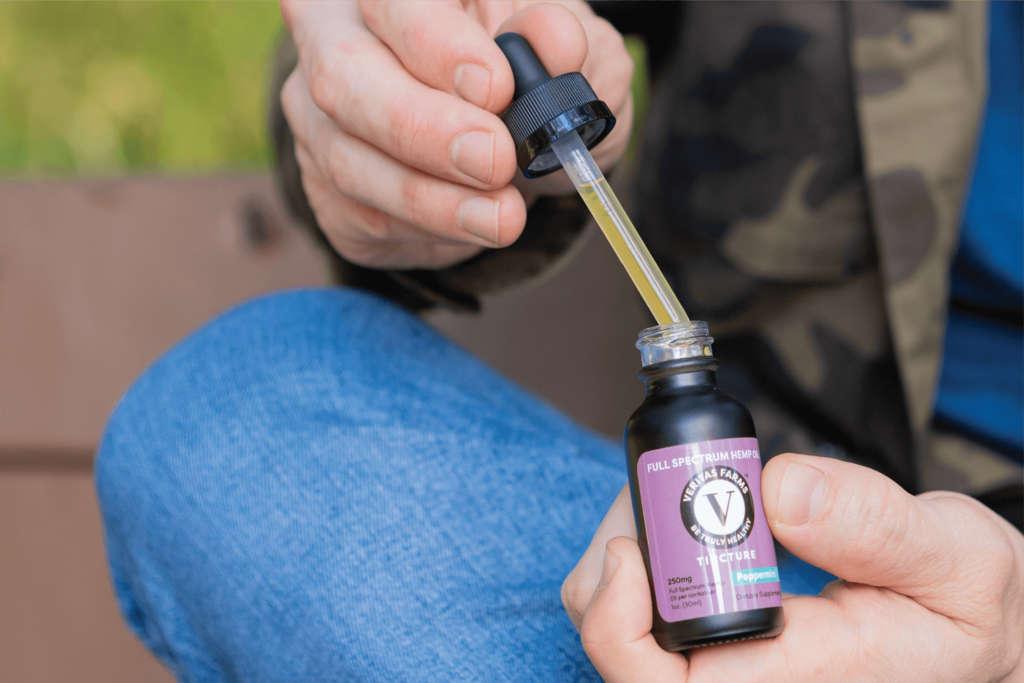 Person with Showing Veritas Farms Tincture Bottle | Veritas Farms